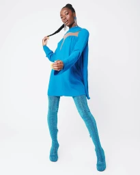 Model in blue tunic dress and sparkly blue over-the-knee boots posing against a plain white studio background.