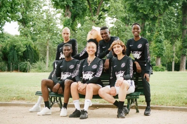 Group of six diverse models wearing black long-sleeve athletic tops posing on a park bench outdoors in London by Danika Magdelena