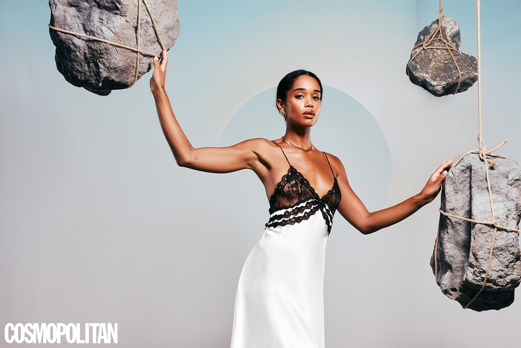 Elegant woman in slip dress poses with suspended rocks against a soft gradient backdrop in a studio, promoting Cosmopolitan magazine.