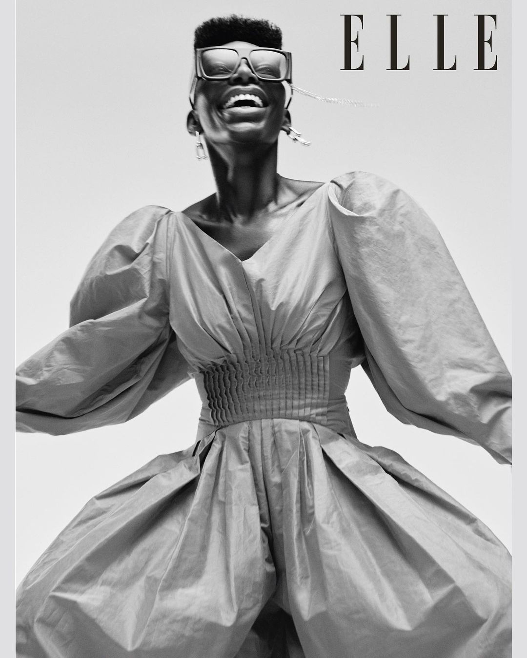 Elle magazine cover featuring an African American woman with short hair and large sunglasses wearing a voluminous blue dress smiling.