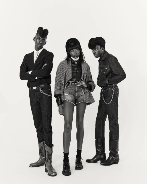 Three young African-descent fashion models in vintage-inspired attire against a light background, showcasing style and unique hairstyles.