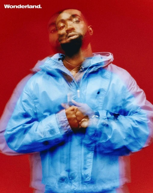 Portrait of a Black man in a blue jacket against a red background, with a blurred double exposure effect, for a Wonderland magazine cover.
