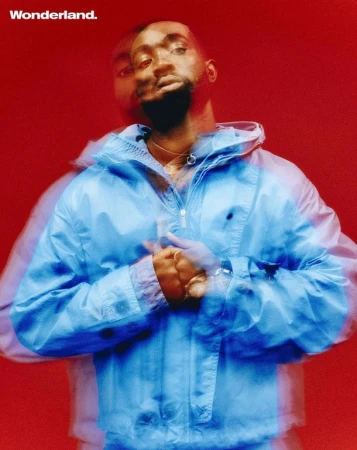 Portrait of a Black man in a blue jacket against a red background, with a blurred double exposure effect, for a Wonderland magazine cover.