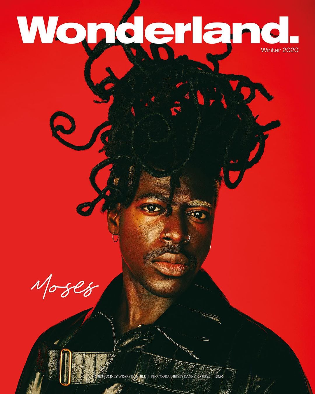Wonderland. magazine cover featuring a young adult Black male model in a black coat with locs, against a bright red background.