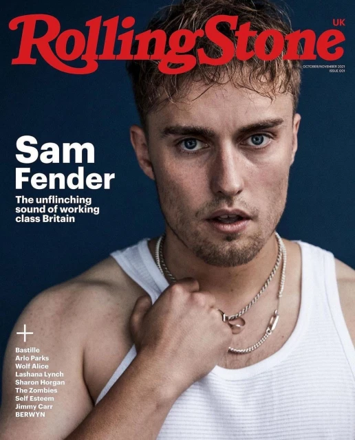 Rolling Stone UK magazine cover featuring Sam Fender in a portrait. He's wearing a white tank top and chain necklaces against a blue background.