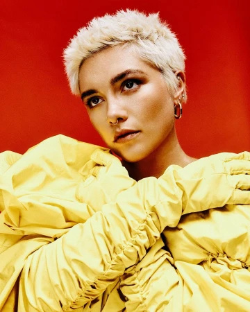 Close-up portrait of a blonde adult female with yellow puffy sleeves against a red background, looking up and to the left.