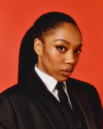 Portrait of a black woman wearing a pinstripe suit jacket and tie against a solid red background
