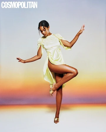 Woman in pale yellow satin dress posing against a gradient sunset backdrop, photographed by Danny Kasirye.