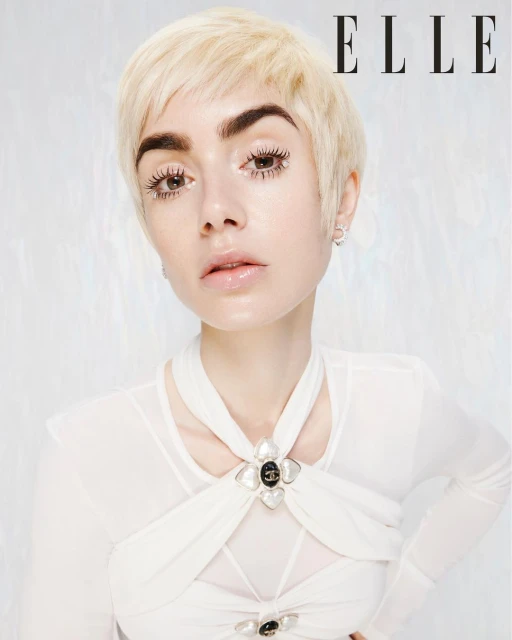 Close-up portrait of a blonde woman with bold eyebrows in a white top, with the 'ELLE' magazine logo in the upper-right corner.