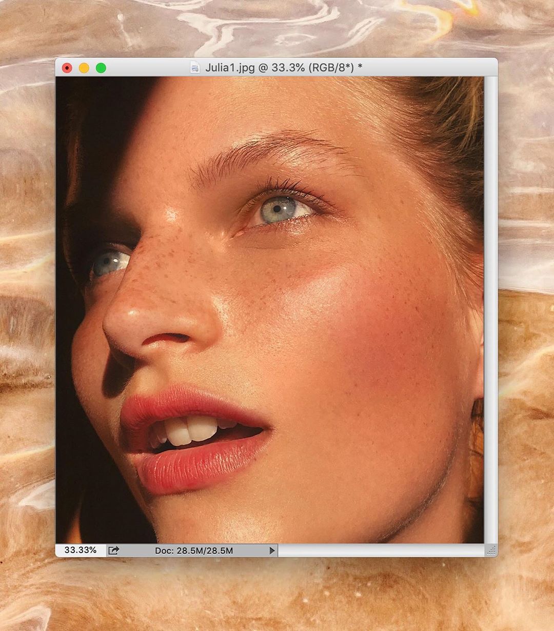 Close-up portrait of a woman with freckles looking slightly upwards to the right, displayed within a computer window on patterned surface.