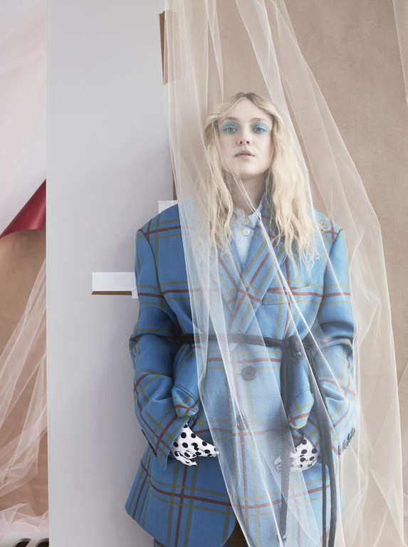 Woman in blue plaid blazer with sheer fabric. Portrait of a woman wearing a plaid blazer, standing indoors with sheer white fabric.
