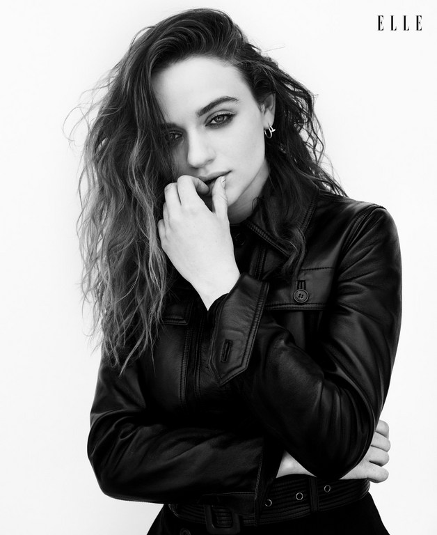 Black and white portrait of a young woman with wavy hair, wearing a leather jacket, holding her hand to her lips, with the ELLE logo.