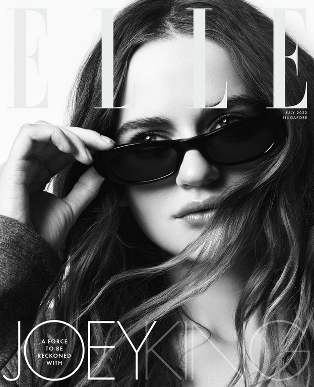 Close-up portrait of Joey King wearing dark sunglasses with long brown hair, photographed by Kerry Hallihan.