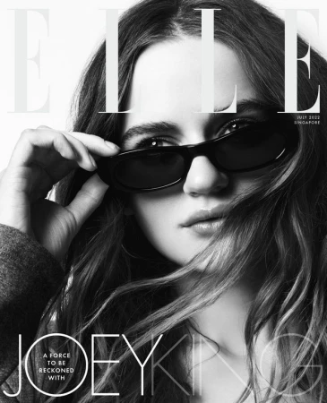 Close-up portrait of Joey King wearing dark sunglasses with long brown hair, photographed by Kerry Hallihan.