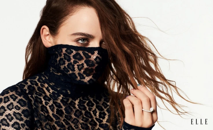 Close-up portrait of a woman wearing a black leopard print lace top covering the lower face against a white background