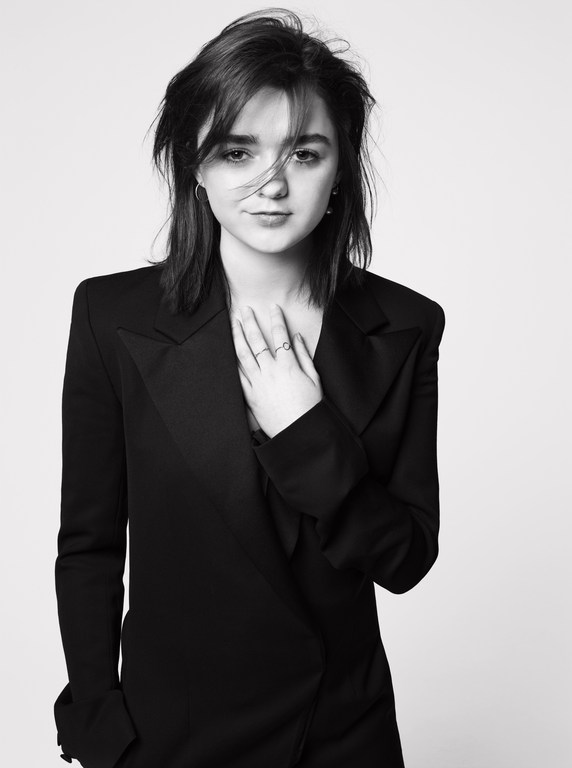 Monochrome portrait of a young woman with dark hair, wearing a black blazer, posing against a bright neutral background in a photo studio.