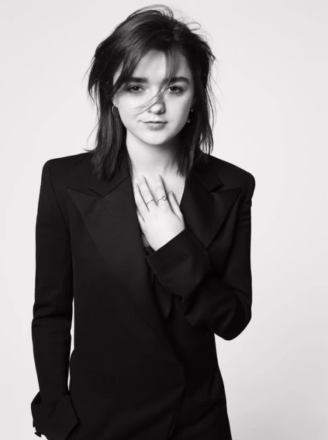 Monochrome portrait of a young woman with dark hair, wearing a black blazer, posing against a bright neutral background in a photo studio.