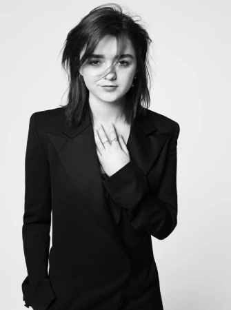 Monochrome portrait of a young woman with dark hair, wearing a black blazer, posing against a bright neutral background in a photo studio.