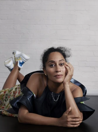 Woman in dark halter top lying on floor with legs kicked up against white brick wall