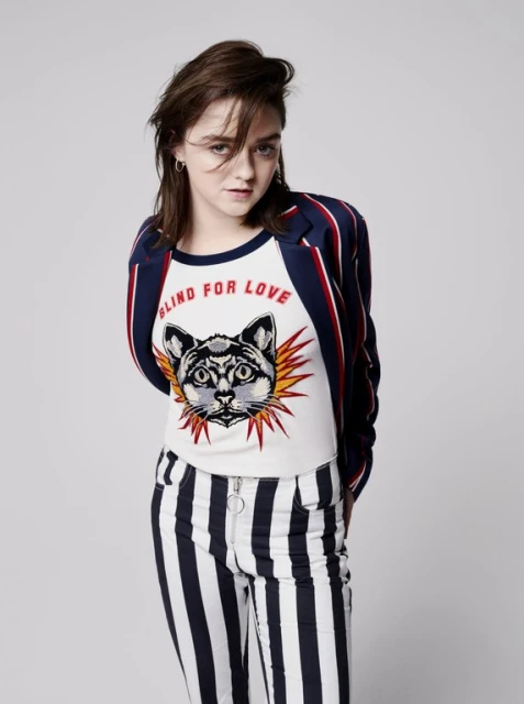 Young woman in a striped blazer poses in a photo studio wearing an animal graphic tee and striped pants with a neutral backdrop.