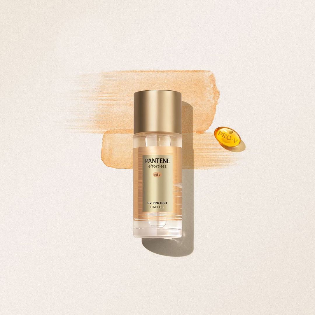 Product shot of Pantene Effortless UV Protect Hair Oil in clear bottle with gold cap and Pro-V capsule on neutral background.