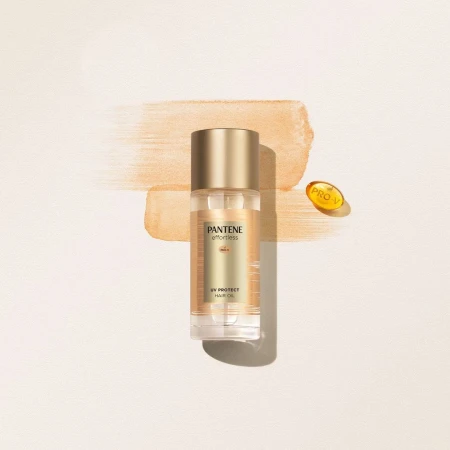 Product shot of Pantene Effortless UV Protect Hair Oil in clear bottle with gold cap and Pro-V capsule on neutral background.