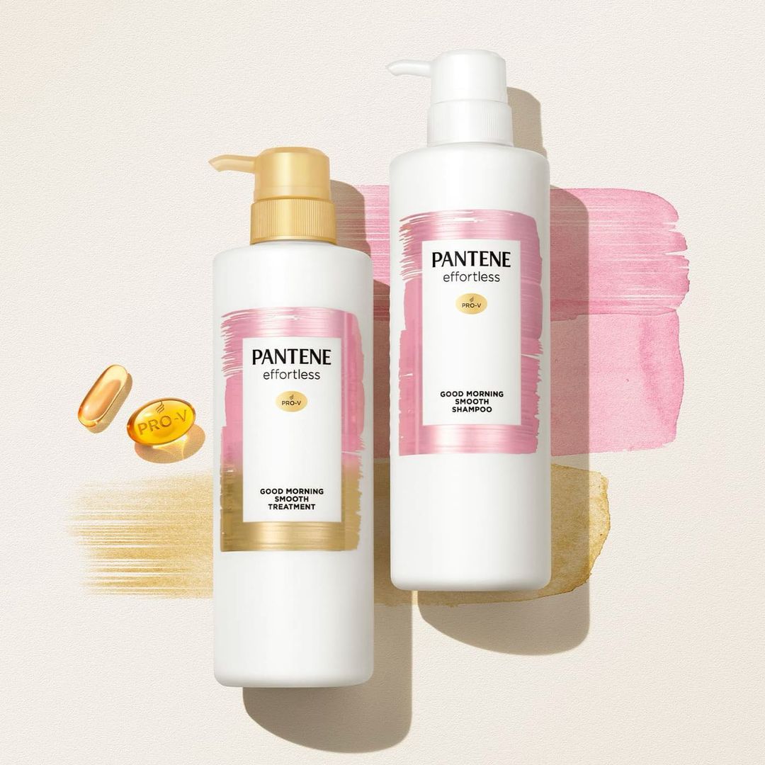 Two bottles of Pantene Effortless hair product, a treatment and shampoo, are arranged against a background with pink and gold accents.