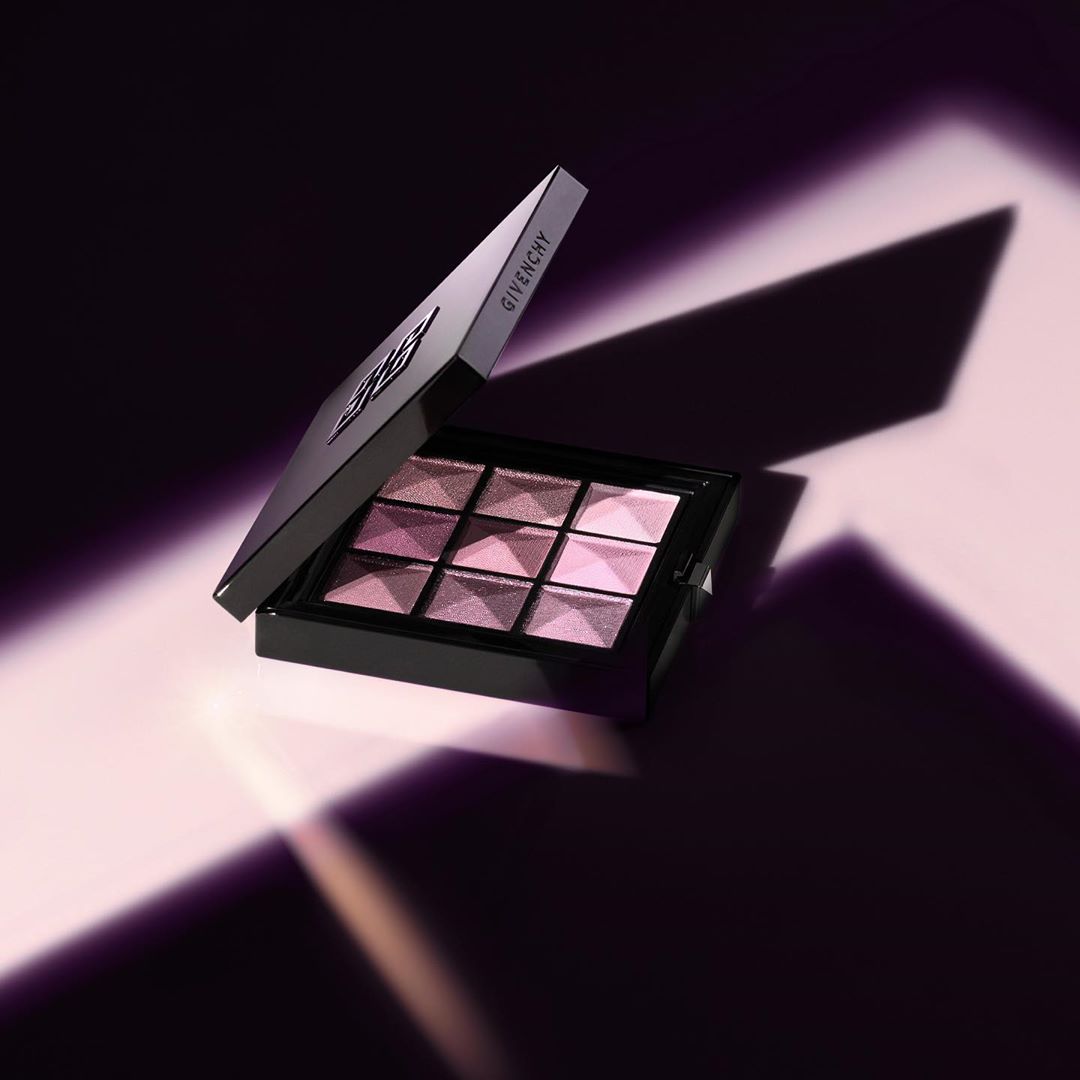 Givenchy eyeshadow palette on a light pink surface with contrasting dark purple shadows, showcasing luxury makeup product.
