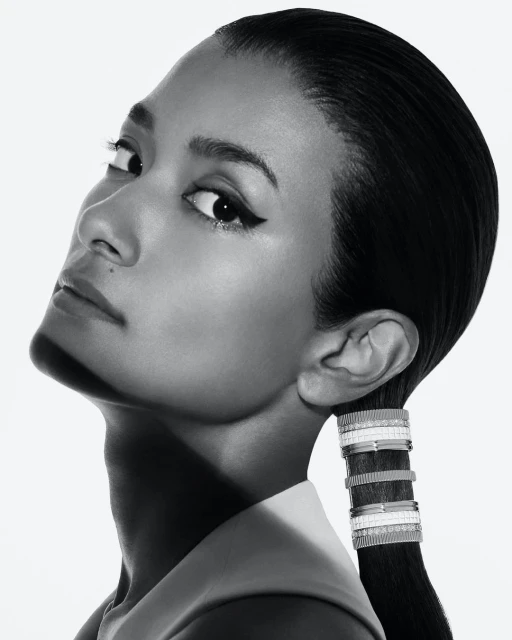 Black and white close-up shot of a woman with sleek hair and jewelry, showcasing her profile against a clean, light backdrop.