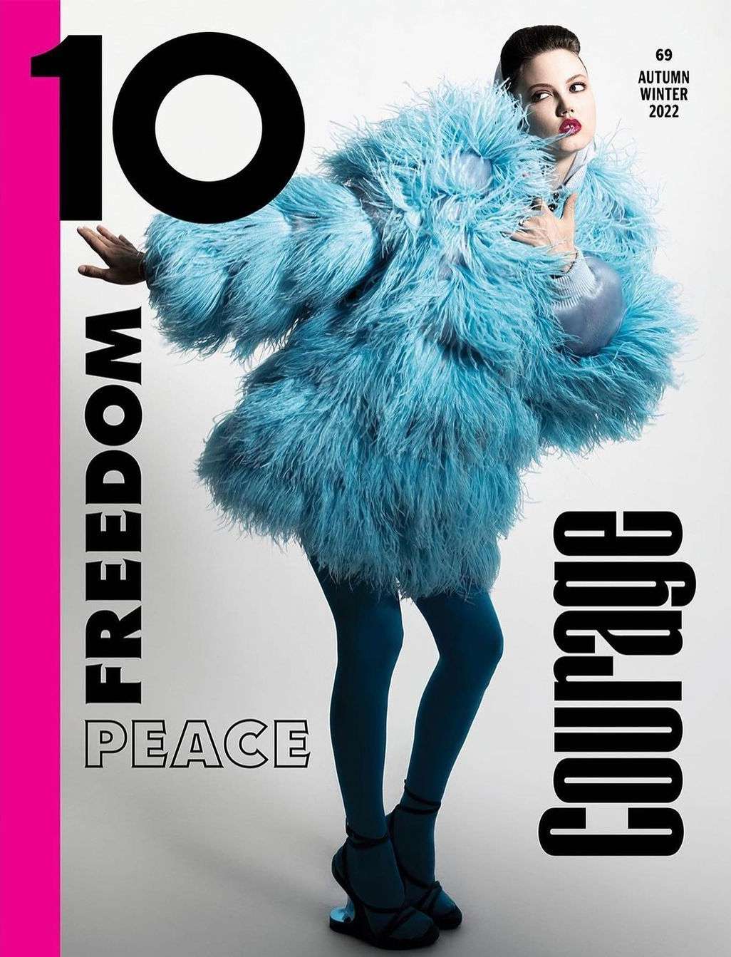 Magazine cover featuring a woman in an extravagant blue feather coat, teal leggings, and black high heels on a neutral background.
