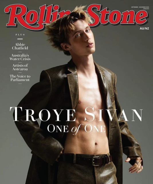 Rolling Stone magazine cover featuring Troye Sivan in a leather jacket and pants, posing shirtless against a grey backdrop with bold magazine text.