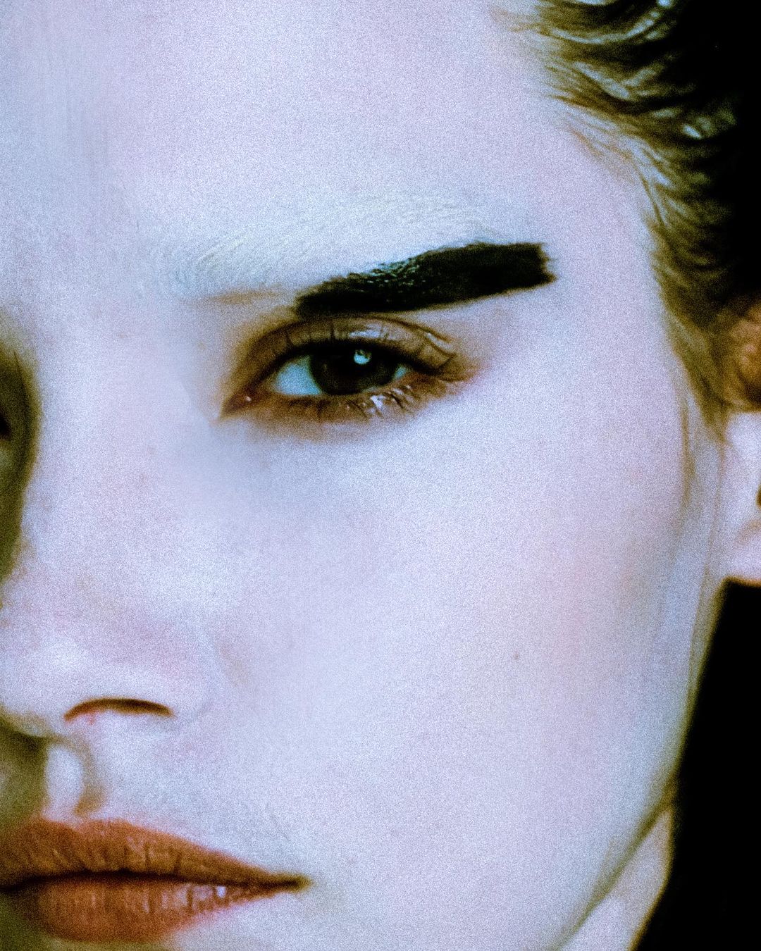 Close-up portrait of an adult female with graphic black eyeliner and exaggerated eyebrow, showcasing bold beauty and makeup artistry.