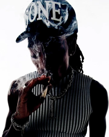 Man wearing a black baseball cap with white text and a ribbed top, smoking against a bright white background.