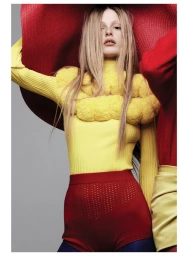Model wearing a yellow ribbed turtleneck top and red high waisted shorts under a massive red brimmed hat.
