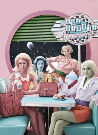 Four women with bold makeup and retro hairstyles pose at a diner with pink and turquoise decor, showcasing purses and donuts.