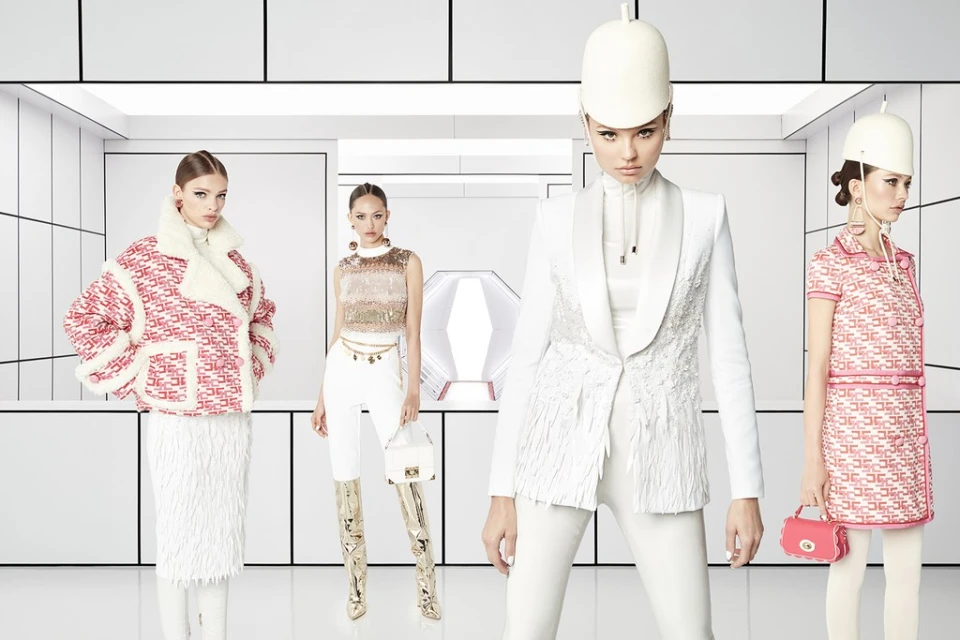 Four fashion models present women's Fall/Winter collection 2024 in studio. Women wear colorful jackets, dresses, skirts and hats. 