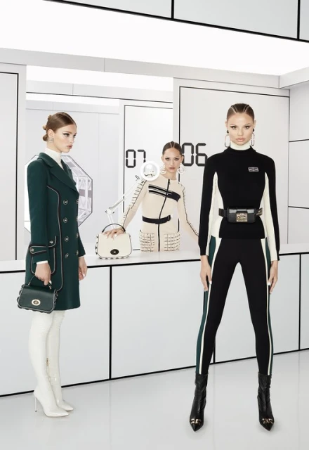 Three fashion models in a bright white space pose in front of a backdrop with geometric shapes and digital-style numbers, showcasing apparel.