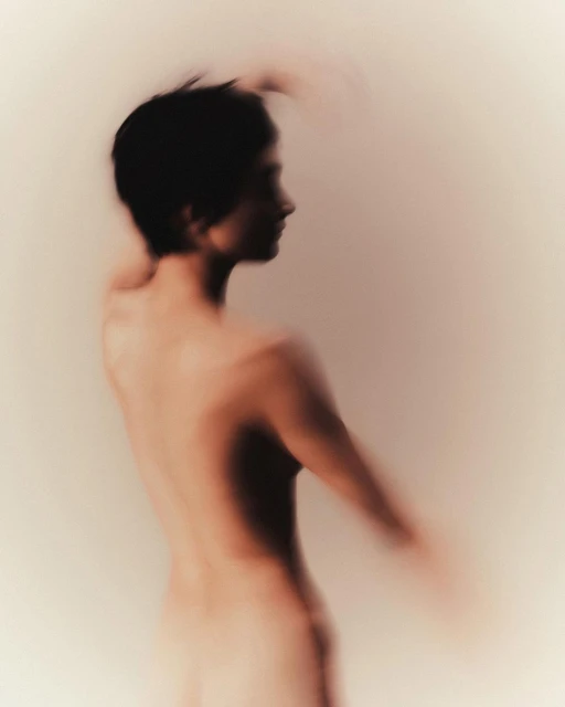 Soft, blurred portrait of a person in profile, featuring delicate hues of beige and brown, with a focus on artistic abstraction.