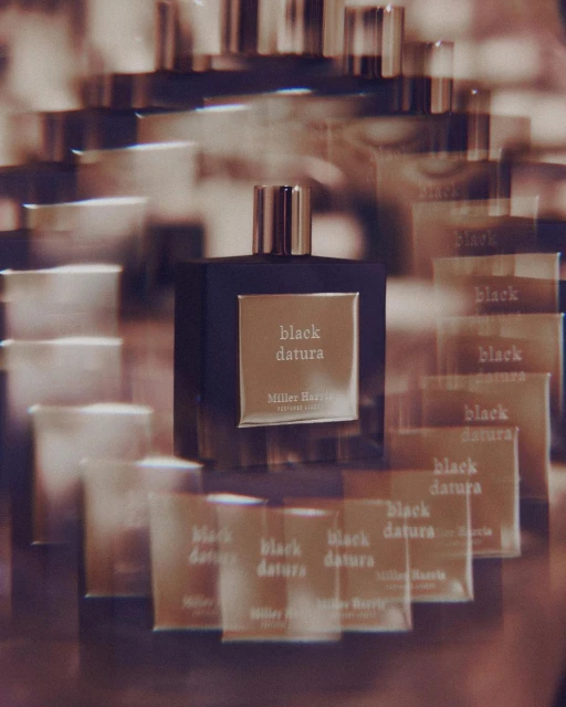 Square bottle of Black Datura by Miller Harris London fragrance. Multiple reflections create a visually complex pattern.