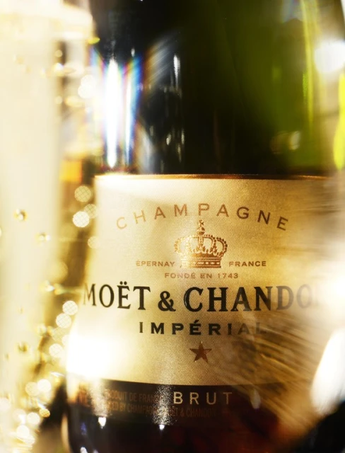 Moët & Chandon Champagne bottle on display with golden label and a gold crown logo, close-up product shot, luxury beverage.