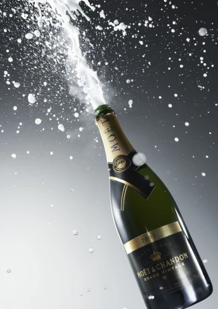 Champagne bottle explodes with foam and splashes against a graduated gray background, showcasing celebration, luxury, and effervescence.