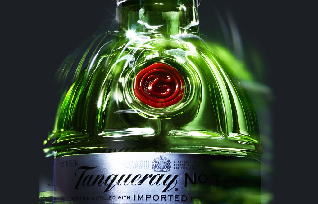 Close-up studio shot of a green glass Tanqueray gin bottle with red wax seal and silver label against a dark gray gradient background.