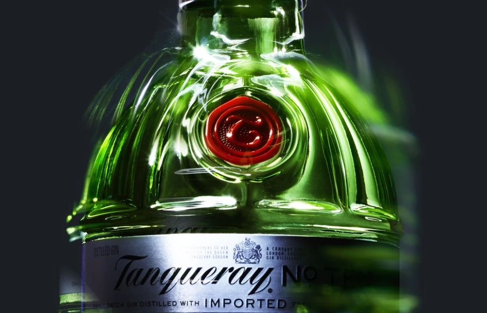 Close-up studio shot of a green glass Tanqueray gin bottle with red wax seal and silver label against a dark gray gradient background.