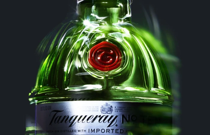 Close-up studio shot of a green glass Tanqueray gin bottle with red wax seal and silver label against a dark gray gradient background.