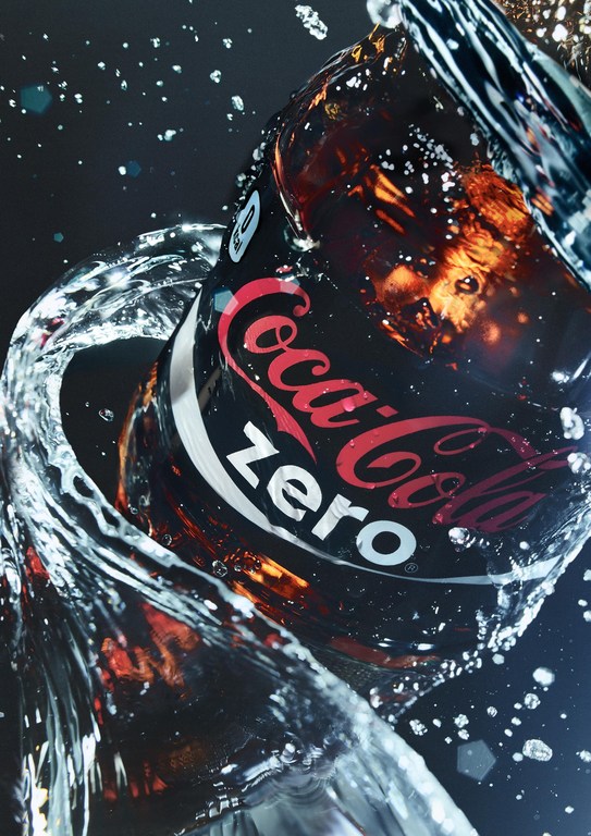 A black Coca-Cola Zero can splashes in clear water, a refreshing beverage advertisement against a dark background.