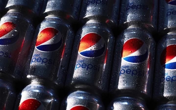 Multiple cans of Diet Pepsi are stacked tightly together, covered with water droplets, showing their blue, red, and silver design.