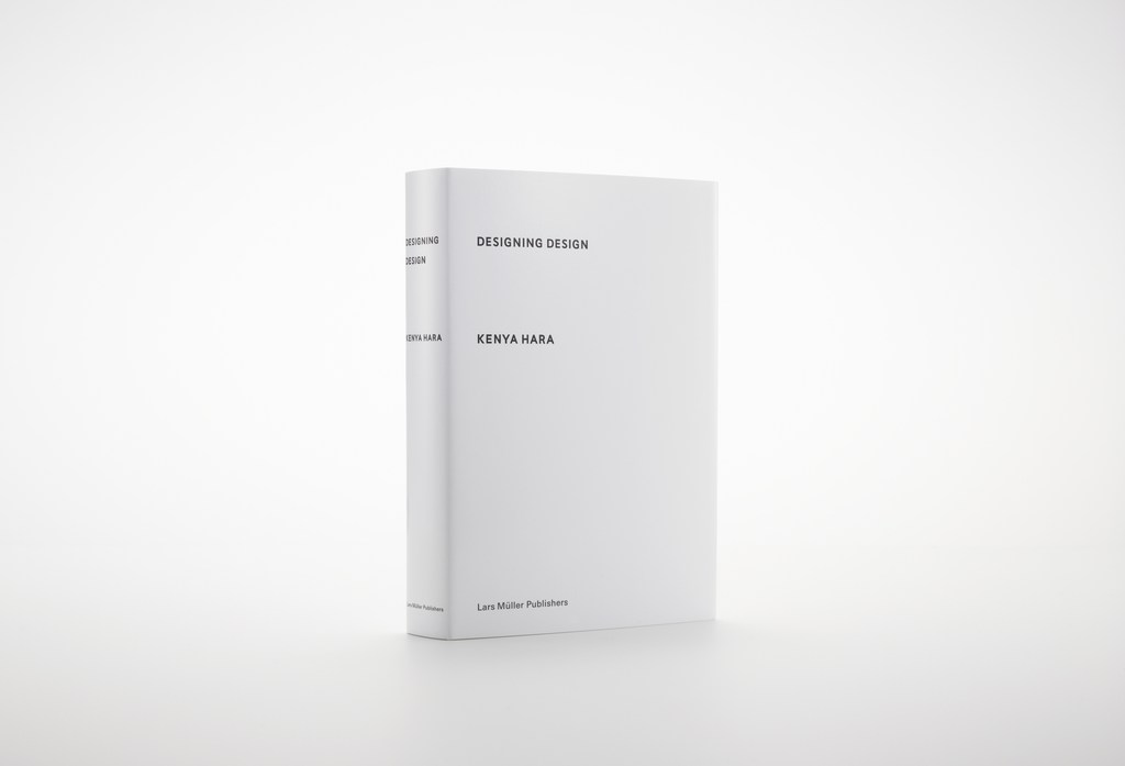 Book titled 'Designing Design' by Kenya Hara on a white surface, featuring a minimalist design and clean typography, standing in a white setting.