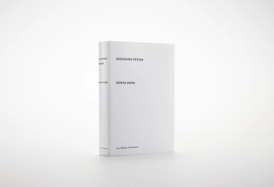 Book titled 'Designing Design' by Kenya Hara on a white surface, featuring a minimalist design and clean typography, standing in a white setting.