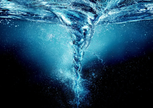 Abstract underwater shot of a swirling vortex of water with light blue and black tones, creating a dynamic, fluid composition.