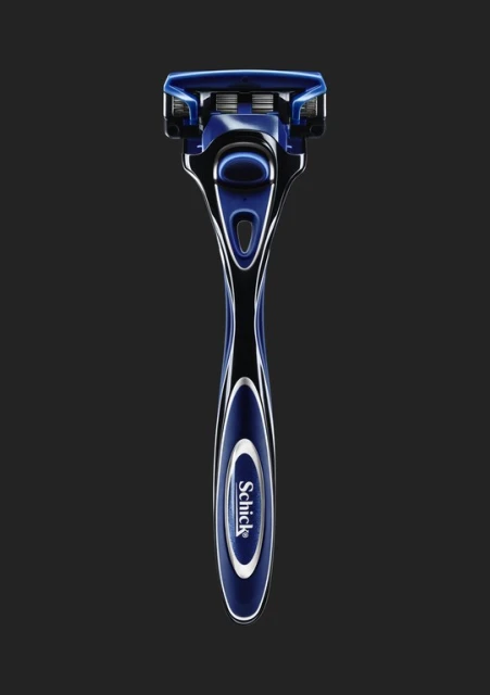 Close-up studio shot of a blue and black Schick razor against a dark background, highlighting the razor's design and features.